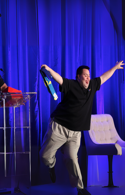 John celebrating on stage, representing building futures through coaching