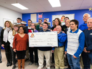 Team presenting a donation check, illustrating giving back